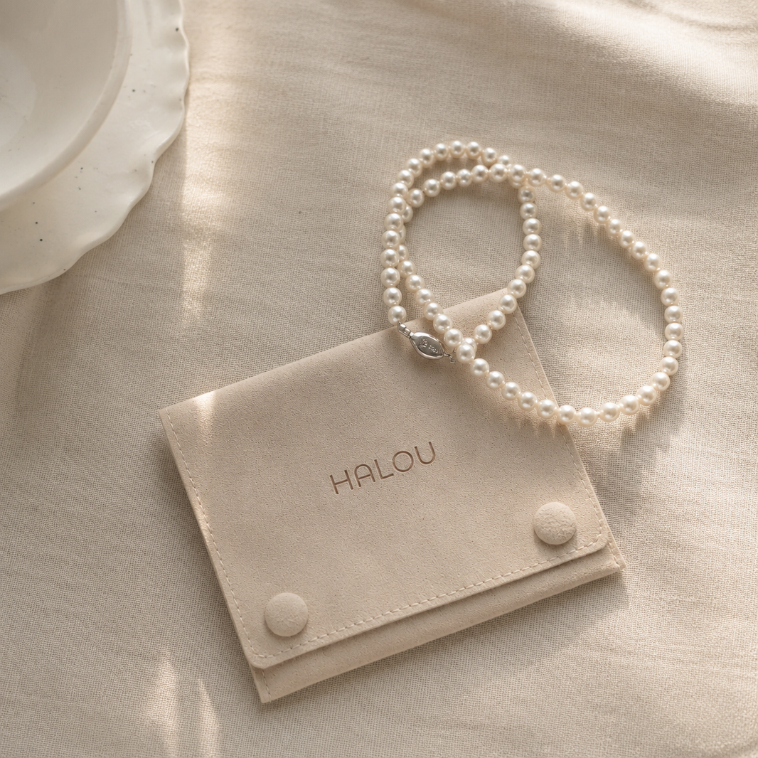Personalized beige microfiber jewelry pouch protecting a pearl necklace